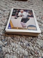 Stack of hockey cards topped by Greg Johnston card in Boston Bruins uniform.