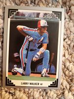 Front of the 1991 Leaf Larry Walker rookie card showing player kneeling with bat, framed by white border with black corner details and Leaf logo.