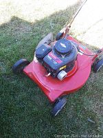 Red Poulin 380 lawn mower with Briggs & Stratton engine on grass showing top and left side.