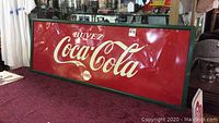 Full front view of red metal Coca-Cola sign with green wood trim, displaying “Buvez Coca-Cola Service”