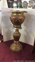 Full view of painted brass plant holder with scalloped top and round base