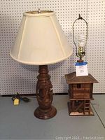 Both lamps side by side on a table against pegboard background showing their shapes and sizes
