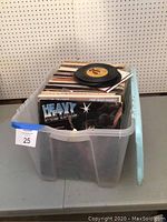 Plastic tote filled with vinyl LP records and some 45 rpm singles on top. Records are stored vertically inside the tote.