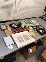 Lot of over 30 small photo frames including black, white, silver, gold, natural wood, and holiday ornament styles displayed on a table.