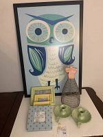 Photo showing large framed owl graphic on foam board, small wire dress form, two mint green enamelware candle holders, and four pastel photo frames of various sizes and patterns.