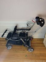 Full side view of the Baby Trend Sit-N-Stand LX double stroller showing the seating area, rear platform, wheels, and folded handle.