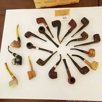 Full view of the lot showing approximately 20 vintage tobacco pipes of varying styles, including briar, corn cob, and novelty carved pipes.