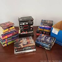 Photo showing multiple stacks of fantasy books on a table, including Twilight series, Black Dagger Brotherhood by J.R. Ward, Sherilynn Kenyon novels, and others.