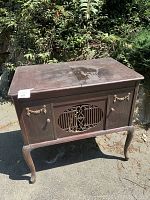 Front view of wooden Victrola turntable console showing brown wood finish with decorative handles and grille.