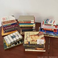 Photo of multiple stacks of books including academic guides, literature, biographies, and language dictionaries.