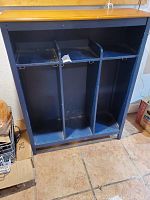 Front view of the wooden mudroom storage cubby showing three vertical compartments with double hooks and upper shelves.