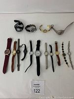 Photo showing 12 vintage women's wrist watches in variety of styles and materials, arranged side by side on a white surface.