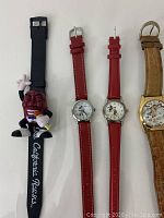 Photo of six wrist watches laid out flat showing Disney and superhero themes, with varied strap materials and styles.