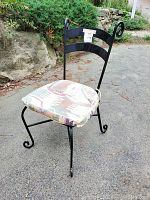 Full view of the black wrought iron chair showcasing its scrolled leg design and the southwestern patterned seat cushion.