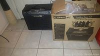 Line 6 Spider Jam 2.0 guitar amplifier next to the original cardboard box showing wear.