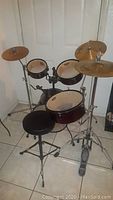 Frontal view of red travel drum set with toms, bass drum, cymbals and throne