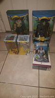 Five Wizard of Oz collectible figures and one Barbie Dorothy doll in original packaging displayed on floor tiles.