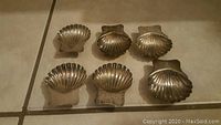 Photo of all six shell shaped dishes arranged on floor showing shell detail and footed bases