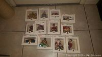 All 12 Spode Christmas tree ornaments unopened in original packaging, arranged on floor tiled surface, showing variety of shapes and colors.