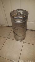 Side view of metal beer keg showing overall shape, Miller logo, and surface wear.