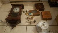 Wide shot showing all items: large wooden Kassel wall clock with pendulum and key, three wooden cigar boxes, two ceramic Toby jugs, four decorative perfume bottles, and two-tier Lefton dish set.