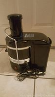 Side view of black Jack LaLanne's Power Juicer showing power cord and locking clamp