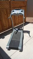 Full view of treadmill showing the walking belt, frame, and upright console, outdoors on concrete.