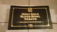 Front cover of black binder with gold foil NFL shield and '22KT Gold Super Bowl Tickets' text