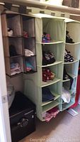Photo showing fabric hanging shelves of various colors filled with folded clothing inside closet, including light green, black, and blue shelves.