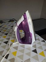 Side view of Black & Decker iron showing purple water reservoir, white handle and soleplate.