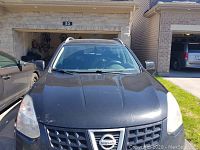 Front exterior view of black Nissan Rogue parked in driveway