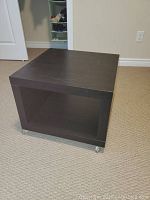 Single black cube-shaped IKEA side table on casters with hollow open center space, minor surface marks visible.