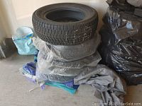 Four winter tires stacked indoors on plastic bags and concrete floor