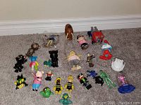 Various small character figurines including Ninja Turtles, SpongeBob, Smurfs, Minions, and others spread on carpeted floor.