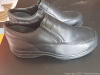 Side view of men's black leather slip-on Red Wing safety shoes showing overall condition and branding on exterior side near heel.