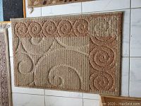 Brown door mat with ornamental swirl pattern