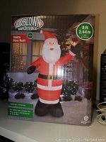 Box packaging showing Airblown Inflatable Santa with specifications like 8 ft height and LED lighting, suitable for indoor and outdoor use.