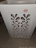White plastic laundry basket with decorative vented pattern on side and Made in Canada sticker