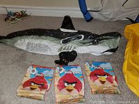 Inflatable orca pool float with three Angry Birds arm floaties on a carpeted floor.