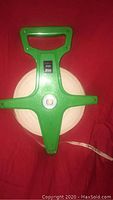 Top view of Champro green plastic measuring tape handle and spool with label 300ft 90m.