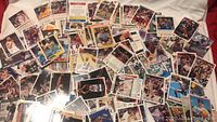 Wide overview of scattered assorted sports cards featuring basketball, baseball, and football players
