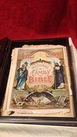 Front title page of the Family Bible showing colorful detailed illustration of biblical figures and decorative elements.