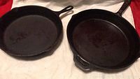 Two cast iron pans side by side, showing the top surfaces and handles