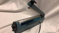 Side view of FS-200 plastic film heat sealer showing lever arm and power cord.