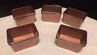Front and top view of five mini rectangular copper pails arranged on a surface.