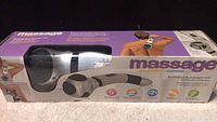 Photo of the boxed rechargeable massager showing the product and usage on back and neck.