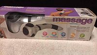 Photo shows the product box with brand name Nassage and product image. The box displays the body massager and highlights features such as 5 massage surfaces, hot-cold compress, 2-year warranty.