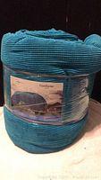 Photo of rolled and packaged Mainstays blue king size comforter in plastic wrapping.