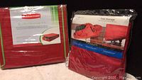 Two sealed Rubbermaid storage products in packaging: XL collapsible storage box and tree storage bag.