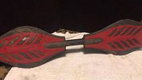 Photo showing entire RIPSTIK caster board deck with red and black grip design and central torsion bar.